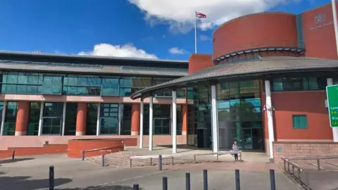 Google Streetview image of the exterior of Preston Crown Court. It is a large glass and red brick building with a round entrance.