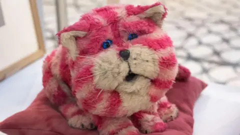 Bagpuss, a pink and white stripped stuffed toy resembling a cat