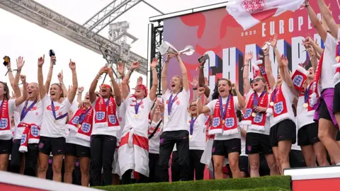 Getty Images Leah Williamson of England lifts the UEFA Women's Euro trophy on stage during the England Women's team victory parade and celebration on 29 July 2025 in London, England.