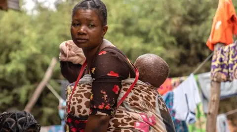 Glody Murhabazi Nzigire Kanigo carrying  a child on her back