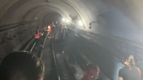 @nnaaddzz8/TikTok Grainy footage shows passengers on track in tunnel as staff in high-viz jackets shine torches