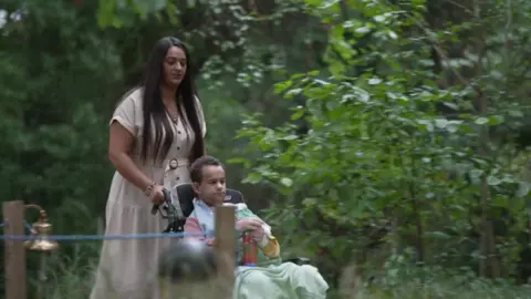 Mum Kareema and son Jayden in the garden with Jayden in a wheelchair